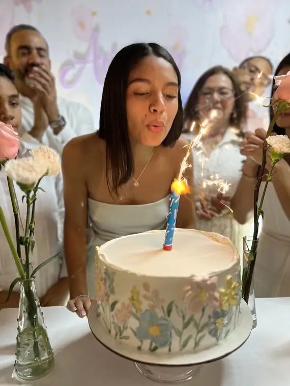 Cumpleañera soplando la vela de su bizcocho con la familia