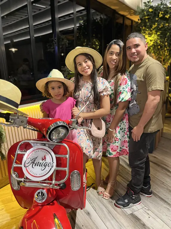 Familia junto a la Vespa roja con el logo de Amigos