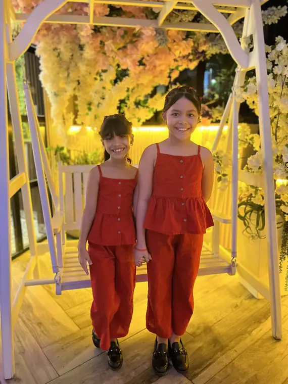 Dos niñas vestidas de rojo frente al columpio de flores