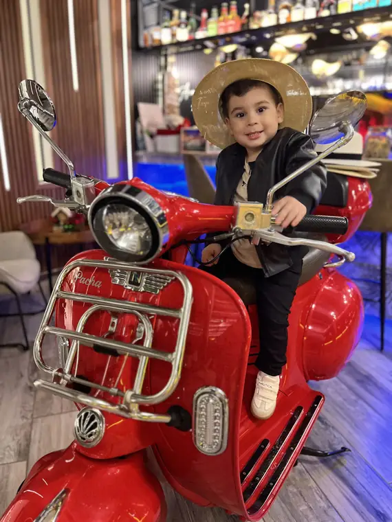 Niño con sombrero en la Vespa roja