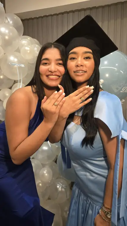 Graduada y amiga mostrando sus anillos