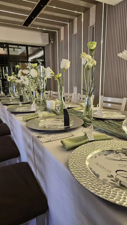 Mesa de boda en verde y blanco con platos de plata y flores
