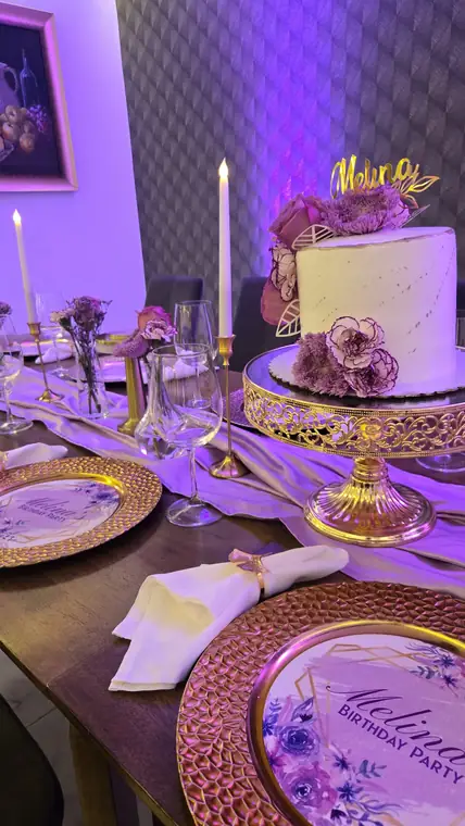 Mesa de cumpleaños con bizcocho, velas y platos dorados