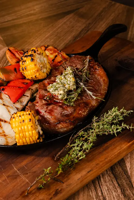 Angus ribeye in a cast iron skillet with grilled vegetables